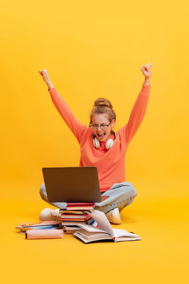 A graduate celebrating in front of a laptop